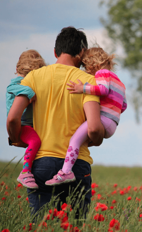 Adult carrying two children in a field